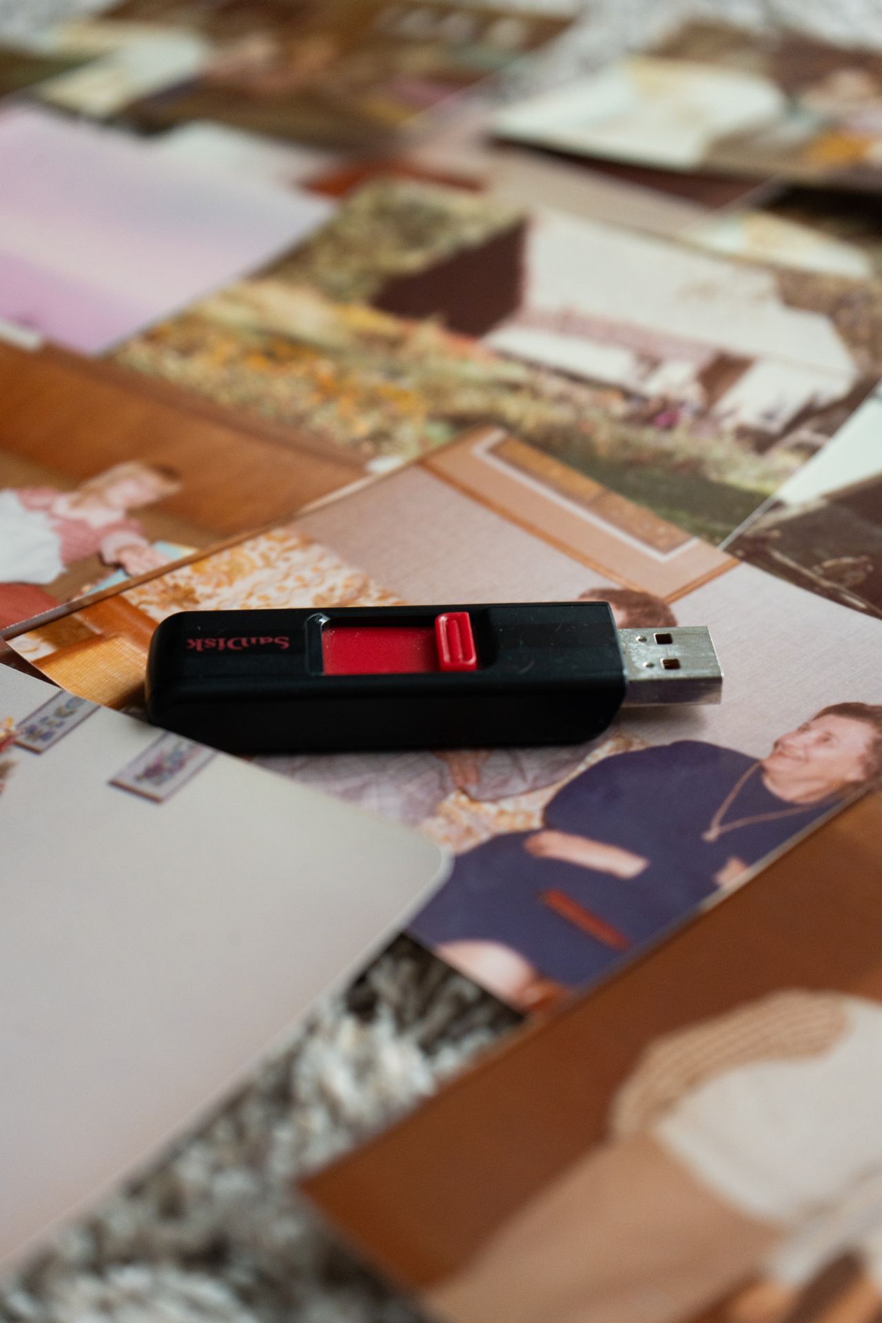 USB drive resting on printed family photographs