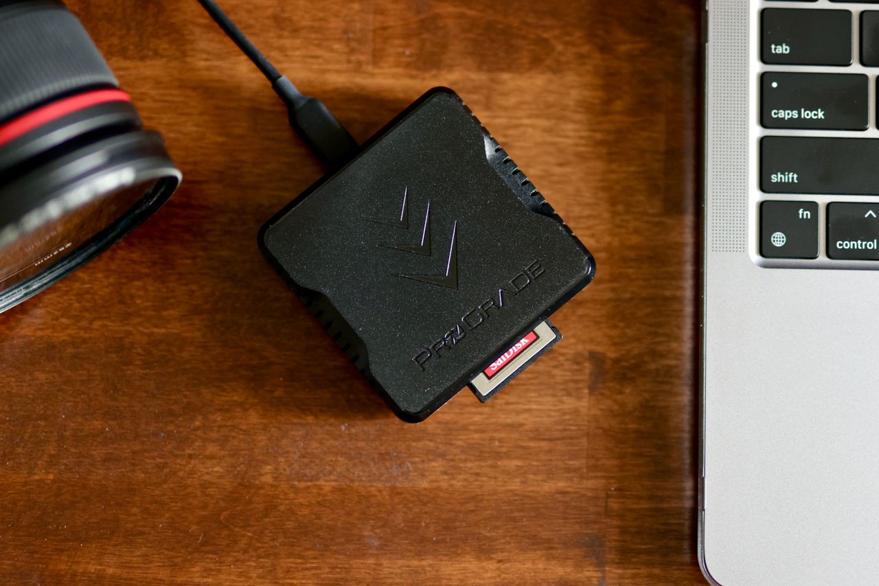 Memory card and card reader beside a camera and laptop