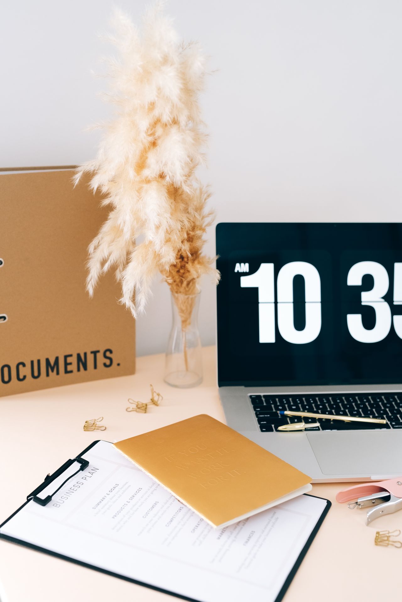 Documents beside a laptop on a desk