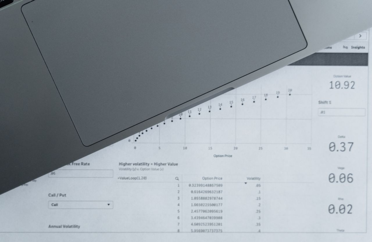 Data tables on paper beside a laptop