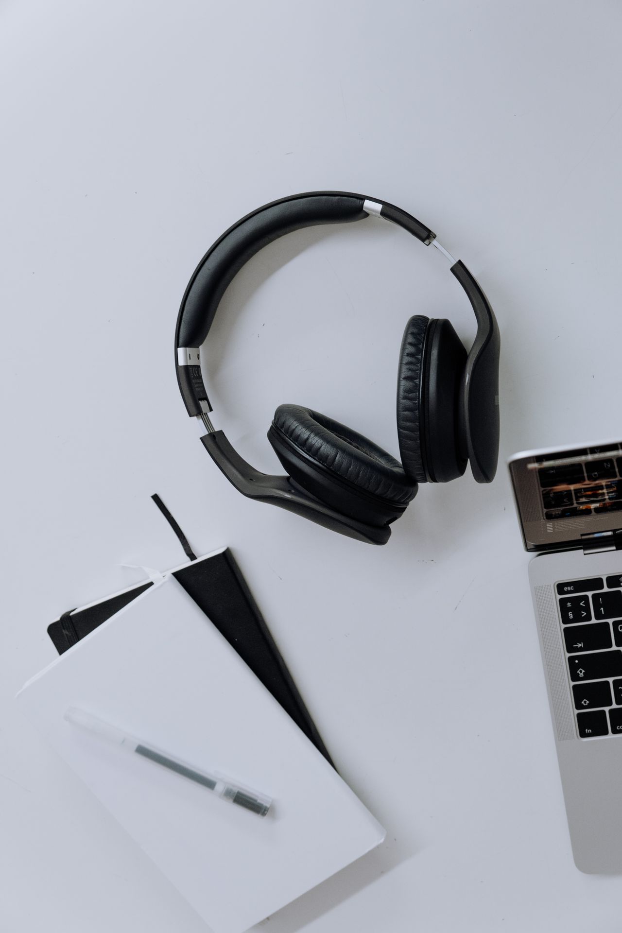 Laptop, headphones and notebook on a work surface