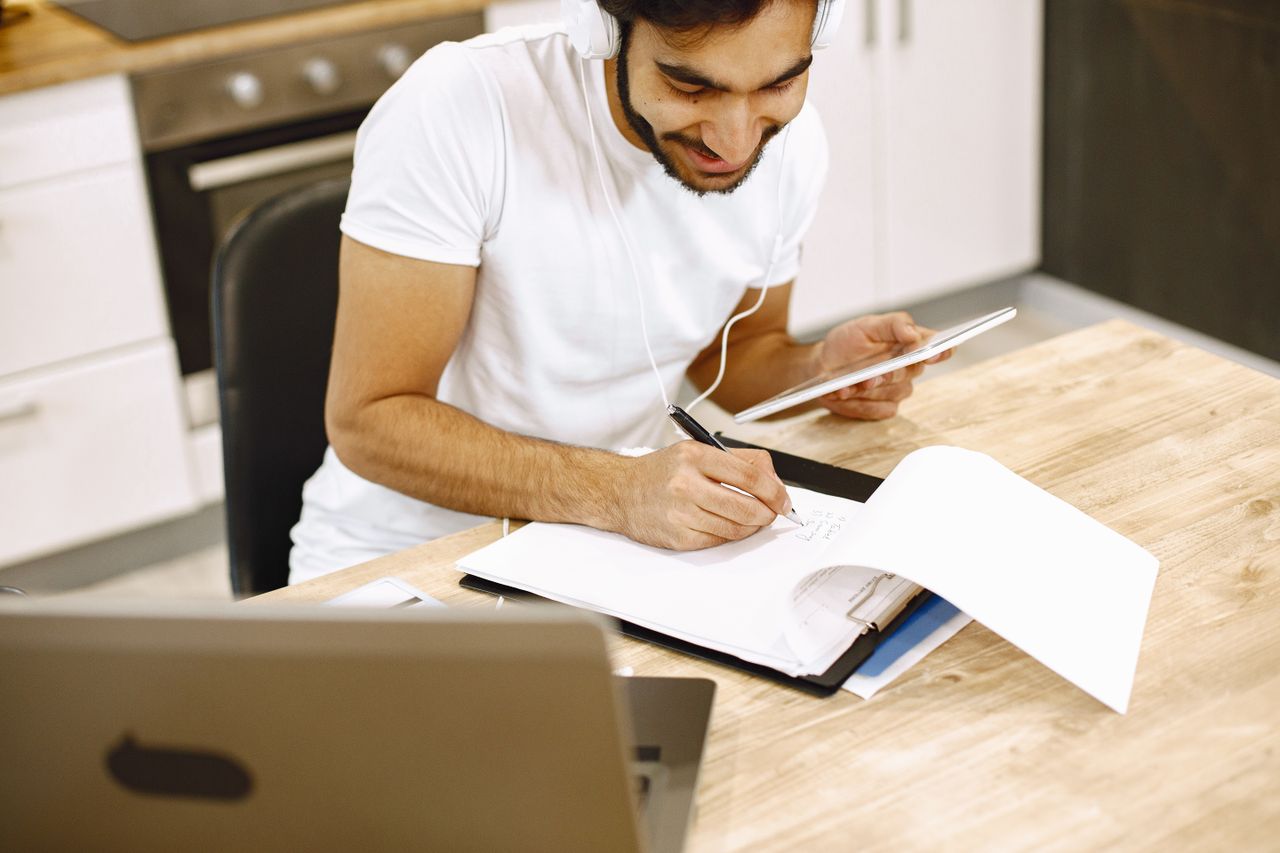 Taking notes with a laptop and tablet at a table