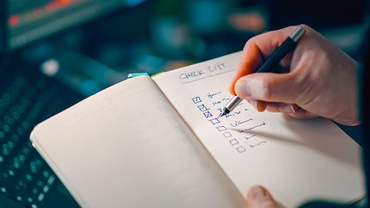 A hand writing a checklist in a notebook